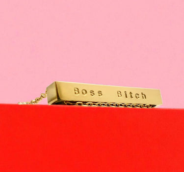 Gold block with 'Boss Bitch' text on a red platform against a pink background